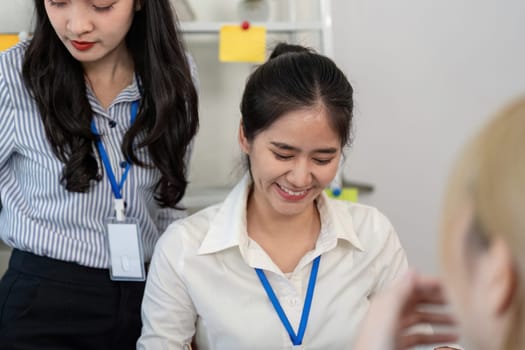 Two women in a modern office share a light moment as they review data, emphasizing teamwork and positive communication.