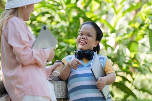 Two friends, one with achondroplasia, engaged in a lively discussion outdoors, sharing ideas and technology in a lush green park.