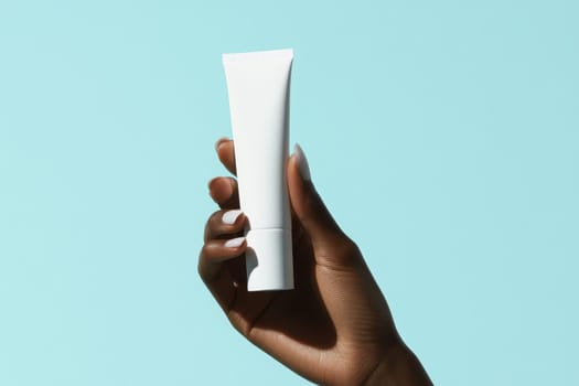 A close-up image of a hand gently squeezing a soft white cosmetic tube against a light blue background, highlighting the product's elegance and simplicity in skincare.