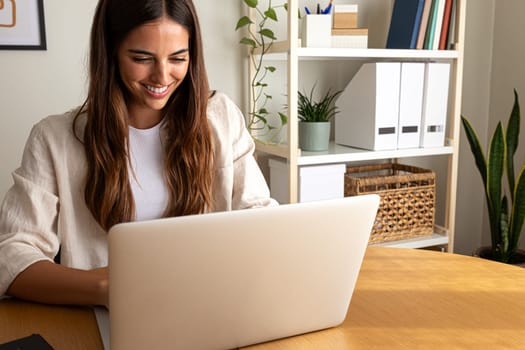 Happy young woman working at home office. Smiling female entrepreneur using laptop. Copy space. Working at home concept.