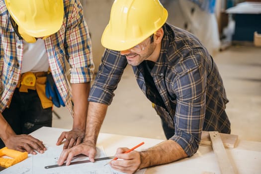 Craftsmen sketch of future project on blueprint paper in woodshop, Carpenter man wear helmet meeting planning a job together at carpentry workshop, team discuss, National Carpenters Day