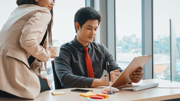 Two business people talk project strategy at office meeting room. Businessman discuss project planning with colleague at modern workplace while having conversation and advice on financial report. Jivy