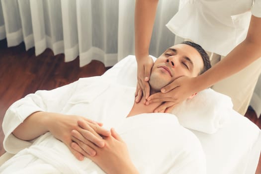 Caucasian man enjoying relaxing anti-stress head massage and pampering facial beauty skin recreation leisure in dayspa modern light ambient at luxury resort or hotel spa salon. Quiescent