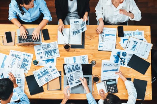 Panorama top view diverse group of business analyst team analyzing financial data report paper on meeting table. Chart and graph dashboard by business intelligence analysis. Meticulous