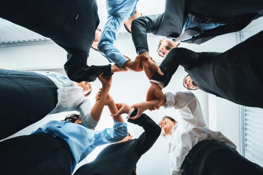 Multicultural business people holding hand together in circle. Unity teamwork in office business workplace. Diverse ethnic office worker engaged in team building. Below view. Habiliment