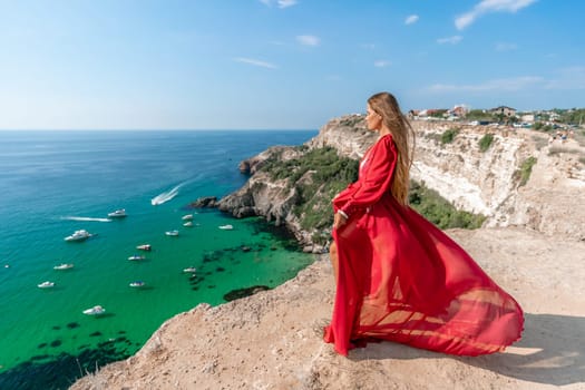 Red Dress Woman sea Cliff. A beautiful woman in a red dress and white swimsuit poses on a cliff overlooking the sea on a sunny day. Boats and yachts dot the background