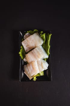 pike perch fillet on a green salad list. Garnish. View from above. Chinese cuisine, hotpot ingredient