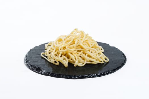 egg noodles on a black plate. Garnish. View from above. Chinese cuisine, hotpot ingredient