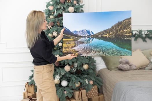 Canvas prints. A woman holding photograph with gallery wrap. Landscape photo printed on glossy synthetic canvas and stretched on wooden stretcher bar.