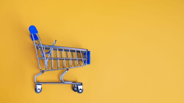 Shopping cart on yellow background with light and shadow. schopping concept.