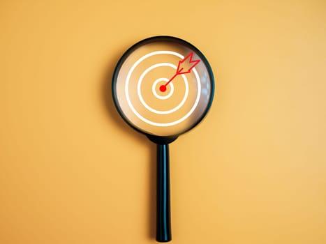 Target, objective, Goal achievement, Purposefulness concept. Magnifying glass focus on dartboard icon over yellow background.
