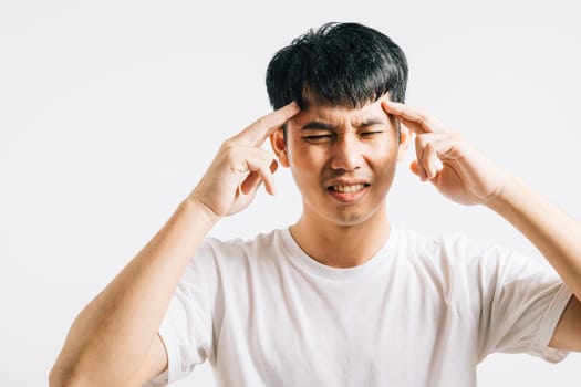 A portrait of a sad and tired man with closed eyes, holding his head in pain due to stress and a headache. Studio shot isolated on white, portraying his struggle with illness.