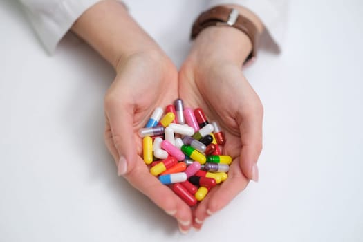 A detailed closeup image of hands holding a vibrant and varied collection of colorful pills and capsules