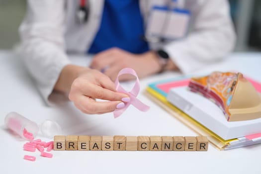 A dedicated healthcare professional proudly holding a pink ribbon in support of breast cancer awareness initiatives