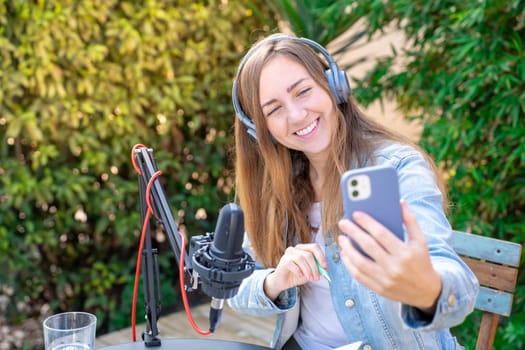 Happy smiling young woman taking selfie with headphones recording podcast. High quality photo