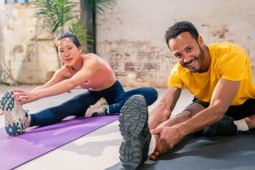 Mixed race sporty man and girl doing exercise together in a industrial gym. High quality photo