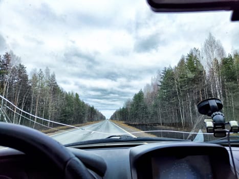 Car salon, windshield, and landscape through damaged windshield. View from seat of driver on nature. The danger of driving faulty car