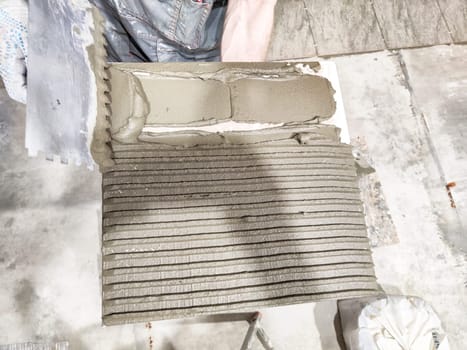 Freshly applied adhesive on a prepared surface showcases the tile repair method in an indoor setting, emphasizing project detail and craftsmanship.