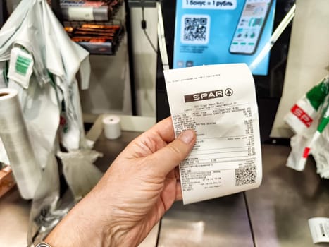 Kazan, Russia - August 27, 2024: Customer holds a receipt at a self-service checkout in a grocery store in Kazan, Russia, showcasing modern shopping technology.