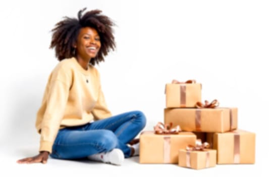 A joyful young woman sits beside neatly wrapped gifts adorned with bows, conveying a festive atmosphere and celebration.. Blurred picture
