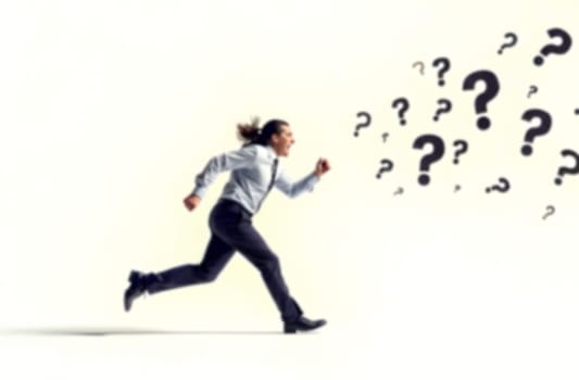 A person in formal attire runs energetically, symbolizing the urgency to address various business challenges represented by question marks. Blurred picture.