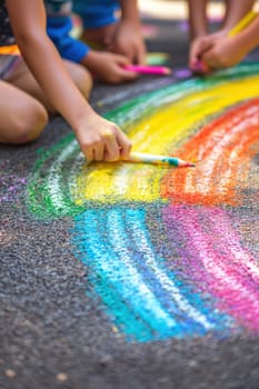 Close-up of a child's hand drawing on the asphalt. Selective focus.