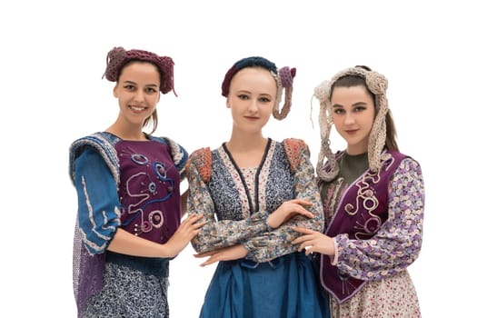 Three women wearing intricate traditional clothing pose together in front of a white background, highlighting their cultural heritage and pride.
