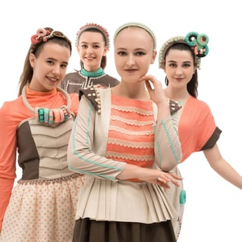 Four fashion models wear colorful, playful outfits and accessories, posing together in a studio setting, highlighting creativity in design.