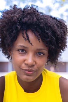 Portrait of black woman with a smiling, Focus on her facial features and natural beauty, captured outdoors with soft lighting and an urban background.