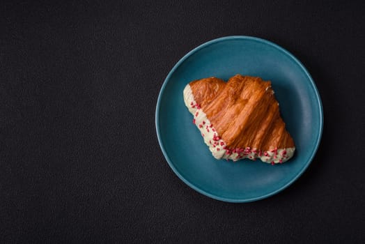 Crispy sweet red croissant with pistachio, raspberry and strawberry on a dark concrete background