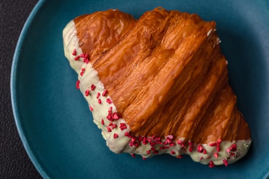 Crispy sweet red croissant with pistachio, raspberry and strawberry on a dark concrete background