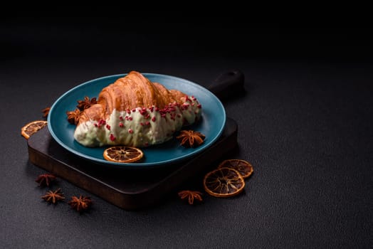 Crispy sweet red croissant with pistachio, raspberry and strawberry on a dark concrete background