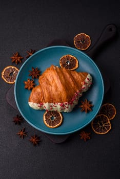 Crispy sweet red croissant with pistachio, raspberry and strawberry on a dark concrete background