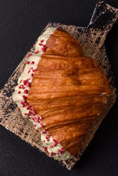Crispy sweet red croissant with pistachio, raspberry and strawberry on a dark concrete background