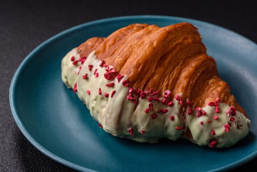 Crispy sweet red croissant with pistachio, raspberry and strawberry on a dark concrete background