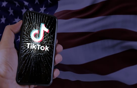 Washington, USA, Jan 18 2024; TikTok logo on a shattered smartphone screen against the American flag. Platform ban in the United States due to national security concerns.