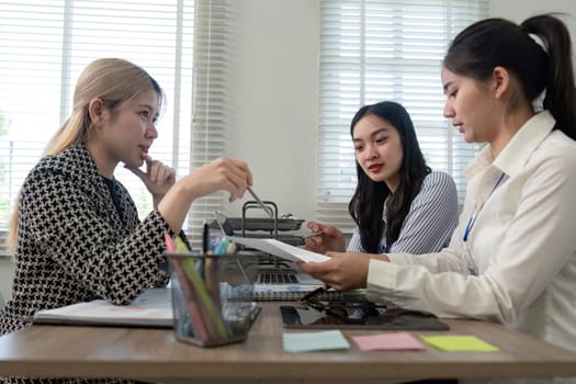 Three professionals engaged in a discussion while reviewing data documents, highlighting teamwork and effective communication in a modern workspace.