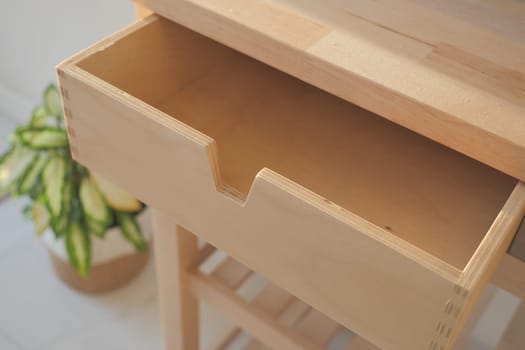 A spacious wooden drawer, beautifully crafted, sits elegantly beside a lush potted plant
