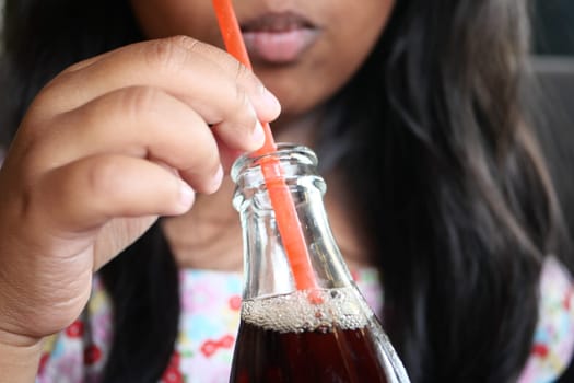 A closeup shot of a person sipping a refreshing drink from a glass bottle during a casual moment
