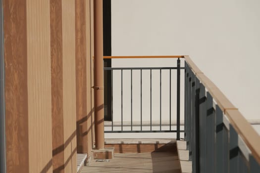 A stylish balcony showcasing wood and metal features, enhanced by warm natural light