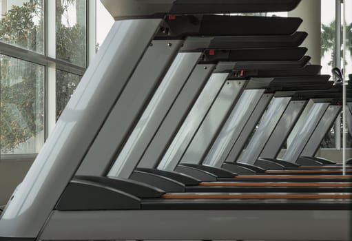 Bangkok, Thailand - Jan 18, 2025 - Side view of Treadmill in the morning with sunlight in fitness center. Perspective view of Treadmill machines, use it as your Wallpaper, Poster and Space for text, Selective focus.