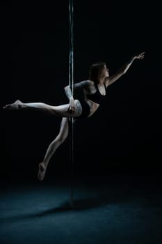 Graceful tattooed girl wearing lingerie dancing on pylon view in the dark room