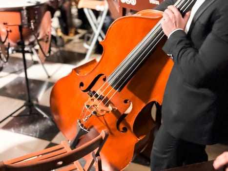 Male musician playing cello at indoor classical music performance.