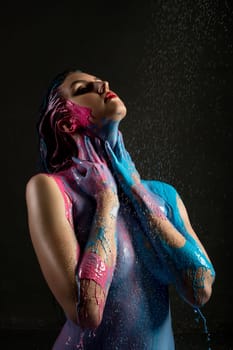Nude woman with colour bodyart view against black background