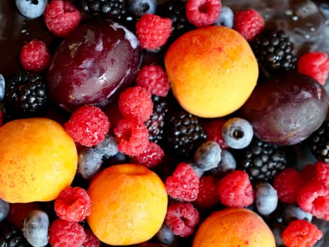 Colored background of seasonal summer fruits apricot, plum, raspberry, blueberry, blackberry in garden, close up