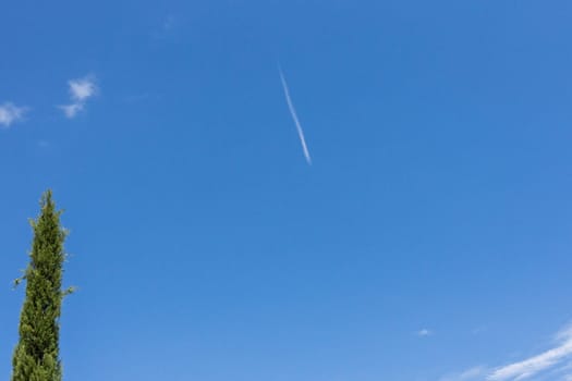 A blurry high-flying passenger plane and white streaks in the blue sky.