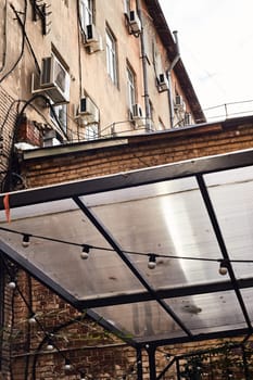 There are garlands of their street lights on the street. In the distance, the facade of an old yellow house. An extension. Terrace.The canopy.