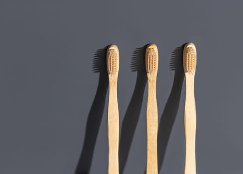 Beige biodegradable bamboo toothbrushes on a grey background with hard shadow closeup, mockup, negative space. Natural personal accessories for dental care, minimal style aesthetic