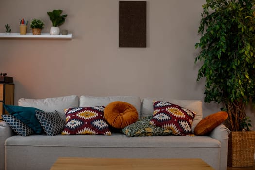 This stylish living area features a plush gray sofa with vibrant cushions and decorative plants for a warm ambiance