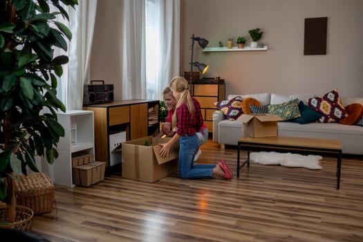 A person unpacks boxes in a modern living room filled with plants and enjoy plenty of natural light
